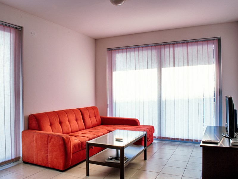 Helles Wohnzimmer mit rotem Sofa und Panoramafenstern in einer Wohnung in Petrovac, Montenegro.