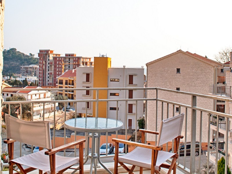 Balkon mit Möbeln und Blick auf die Stadt in einer Wohnung, Petrovac, Montenegro. Gemütliche Sitzecke im Freien.