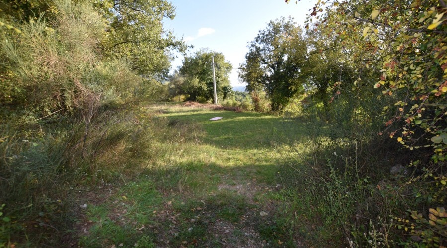 Building plot surrounded by greenery, Kavac village, Montenegro. View of a flat area with trees.