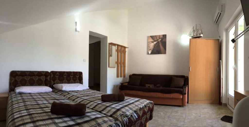 Spavaća soba u mini-hotelu Meline, Bokokotorski zaliv, Crna Gora: dva kreveta, sofa, ormar i izlaz na terasu.