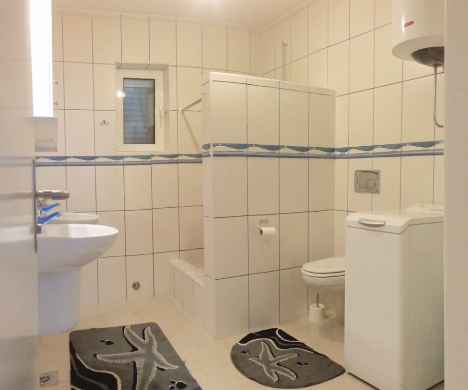 Svetlo kupatilo sa tuš kabinom i veš mašinom u mini-hotelu, Meline, Bokokotorski zaliv, Crna Gora.