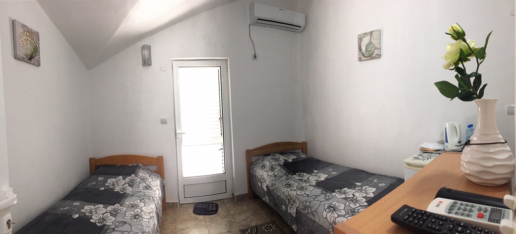 Spavaća soba sa dva kreveta u hotelu, Meljine, Bokokotorski zaliv, Crna Gora: svetao enterijer, klima-uređaj i izlaz na balkon.