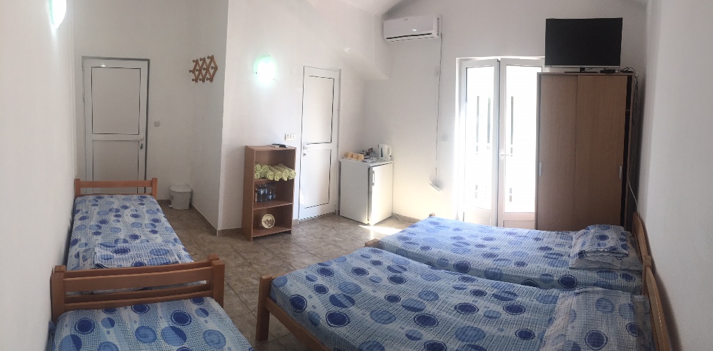 Trokrevetna soba u hotelu Meline, Crna Gora: tri kreveta, ormar, frižider, klima-uređaj i svetla obrada zidova.