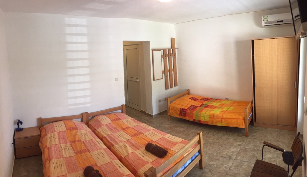 Spavaća soba u mini-hotelu Meline, Bokokotorski zaliv, Crna Gora: tri drvena kreveta, ormar i klima-uređaj.