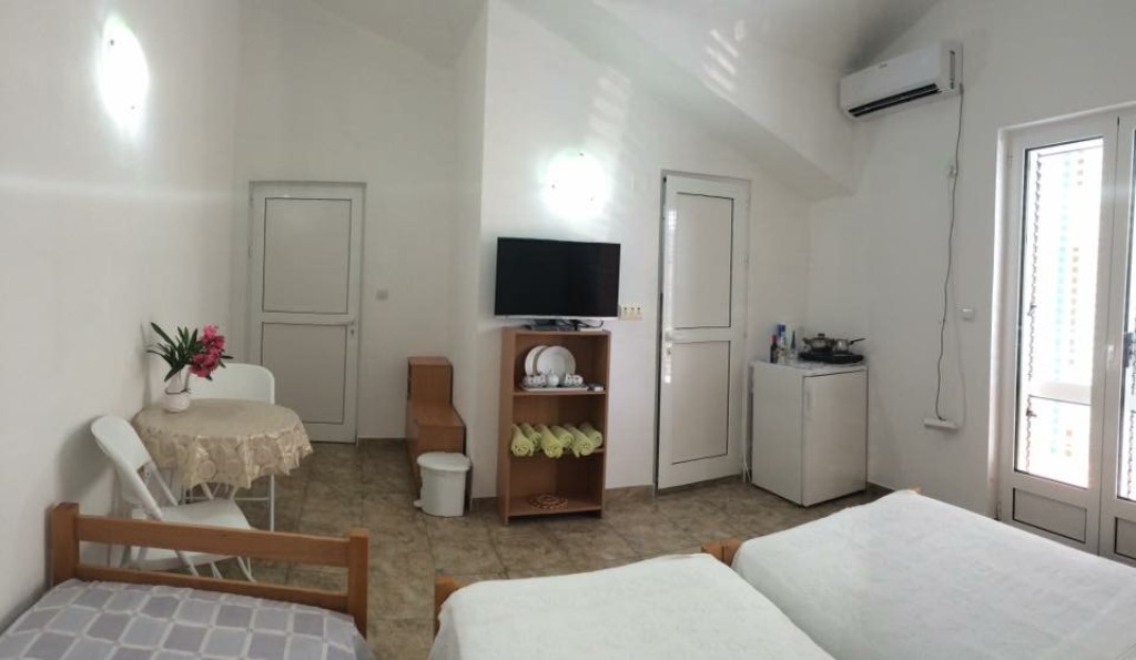 Svetla soba u mini-hotelu Meline, Bokokotorski zaliv, Crna Gora: dva kreveta, TV, frižider i trpezarijski deo.