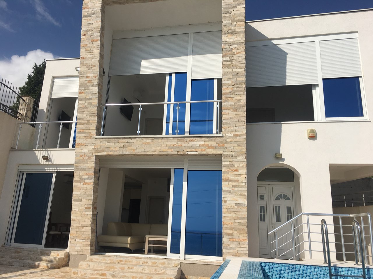Moderne Villa mit Pool und Panoramafenstern in Šušanj, Bar Riviera, Montenegro. Fassade aus Stein und Glas.