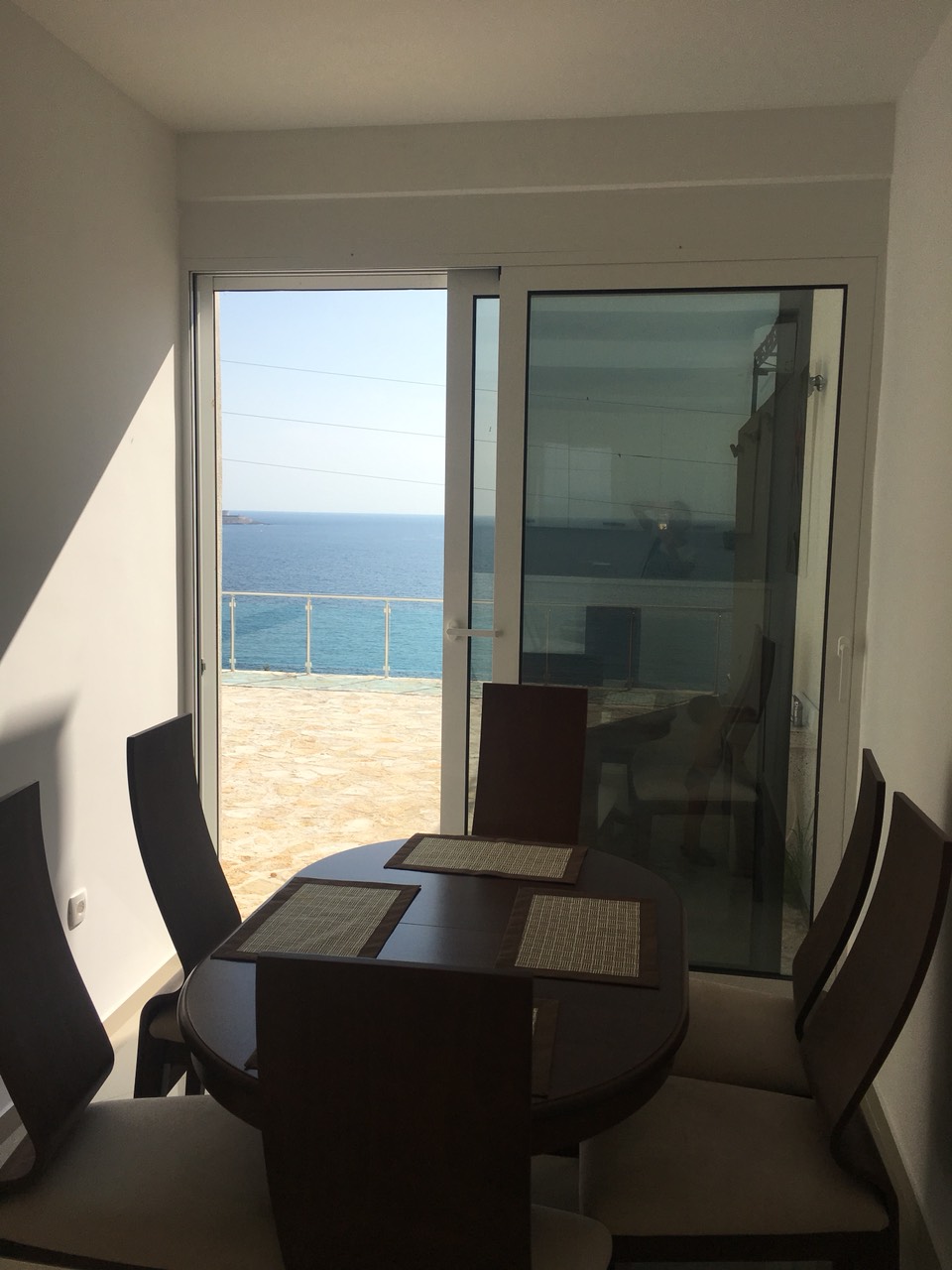 Essbereich im Haus an der Barer Riviera, Montenegro: Tisch mit Blick auf das Meer und die Terrasse durch Panoramatüren.
