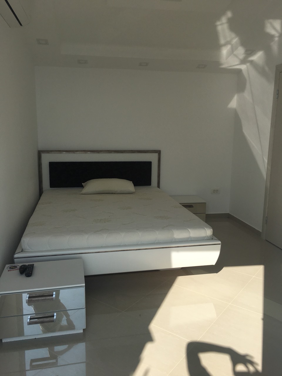 Modernes Schlafzimmer mit Doppelbett und glänzenden Nachttischen im Haus, Barska Riviera, Montenegro.