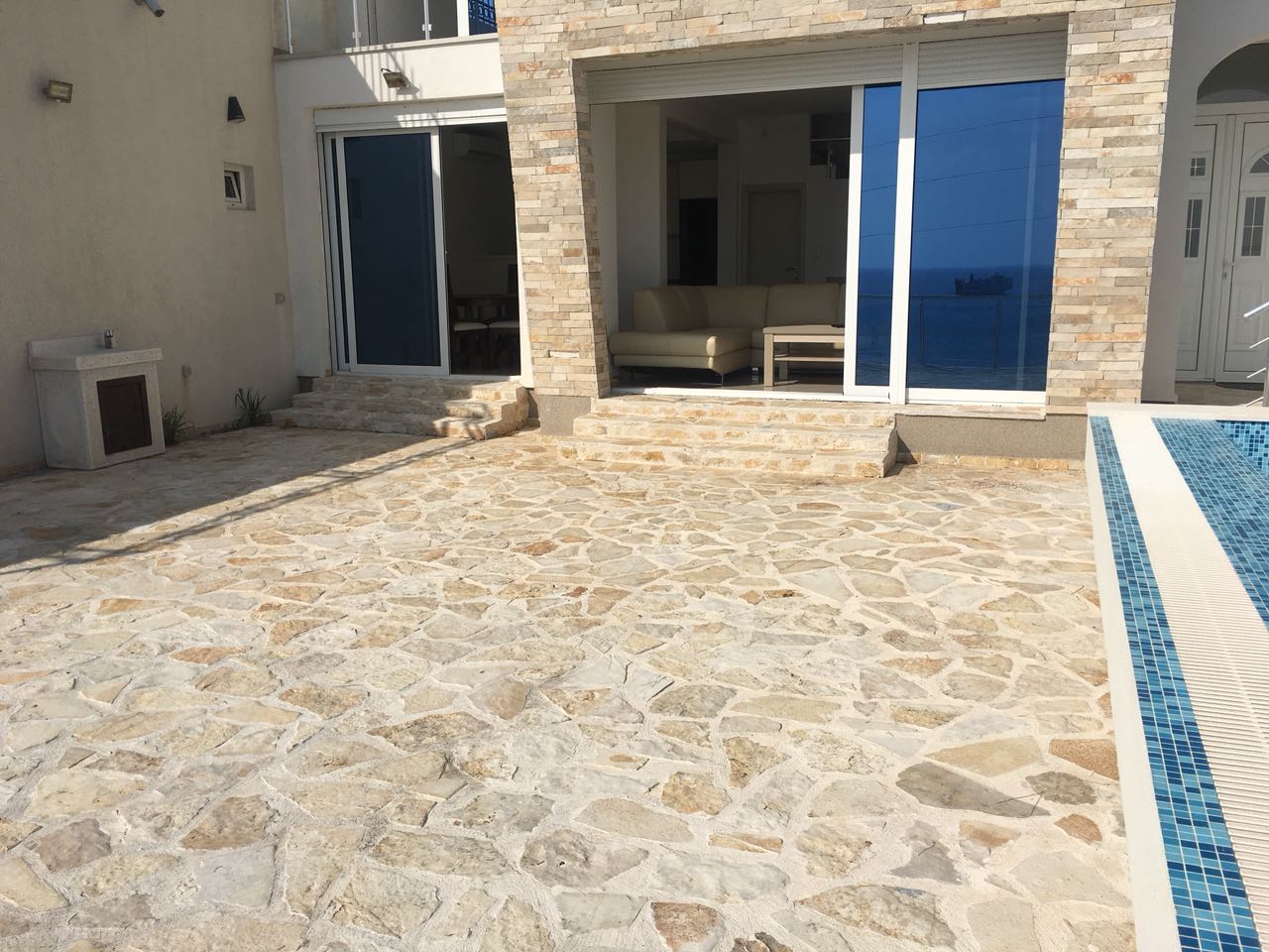 Terrasse mit Pool und Meerblick am Haus in Šušanj, Bar Riviera, Montenegro: Steinverkleidung und Panoramafenster.