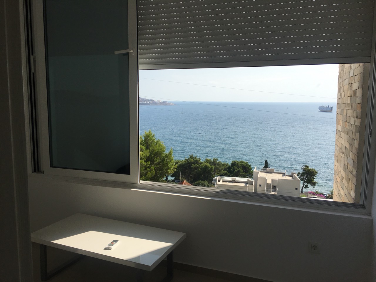 Meerblick aus dem Wohnzimmer eines Hauses in Šušanj, Bar Riviera, Montenegro: weiße Möbel und Panoramafenster.