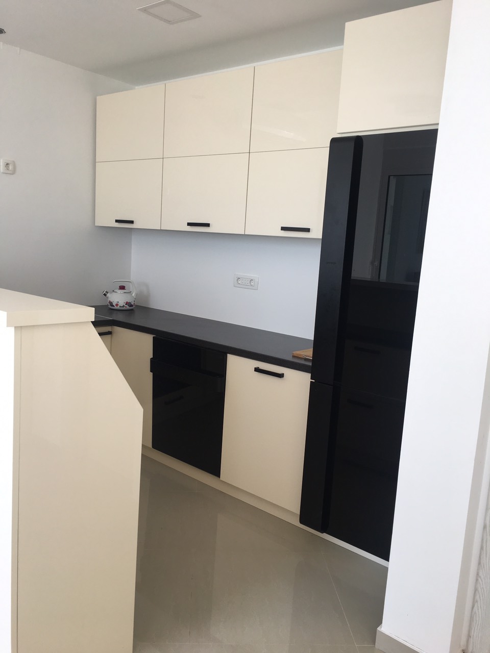 Moderne Küche im Haus, Barska Riviera, Montenegro: weiße Fronten, schwarze Geräte und Arbeitsplatte, Fliesenboden.