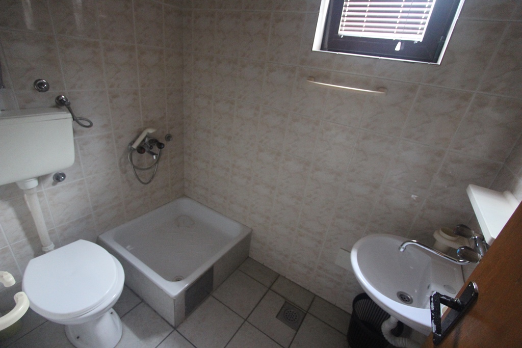 Badezimmer in einem Mini-Hotel in Baošići, Montenegro: Duschwanne, Waschbecken, Toilette und helle Wandfliesen.