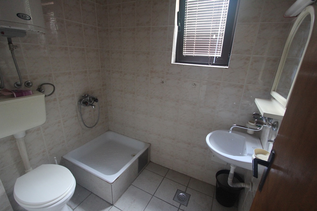 Badezimmer in einem Mini-Hotel in Baošići, Montenegro: helle Fliesen, Duschwanne, Waschbecken und Boiler.