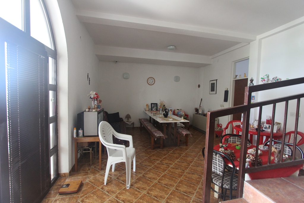 Wohnzimmer in einem Mini-Hotel in Baošići, Montenegro: Essbereich mit Holztisch, Fliesenboden und Bogenfenster.