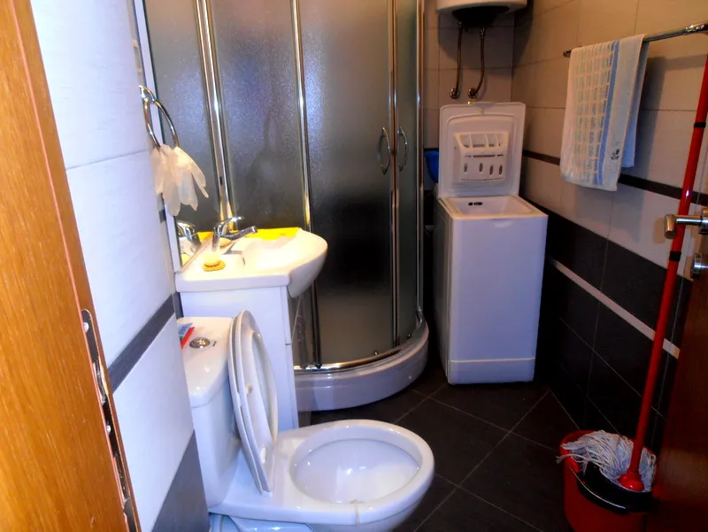 Kupatilo u stanu u Herceg Novom, Crna Gora: tuš kabina, lavabo, WC šolja i veš mašina.