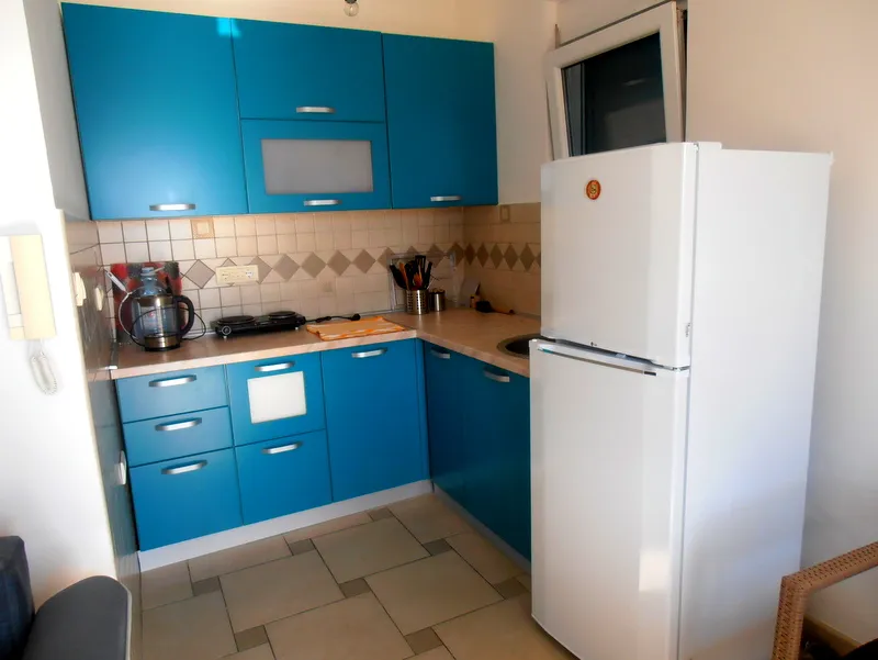 Kompaktna kuhinja sa plavim nameštajem i belim frižiderom u stanu na prodaju, Herceg Novi, Crna Gora.