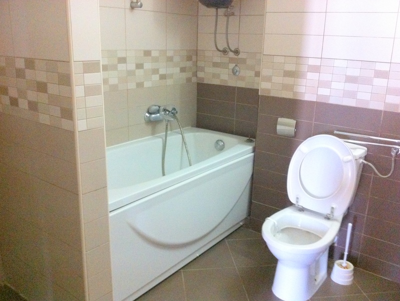 Modernes Badezimmer mit weißer Badewanne und Fliesen in Beigetönen in einer Wohnung, Herceg Novi, Montenegro.