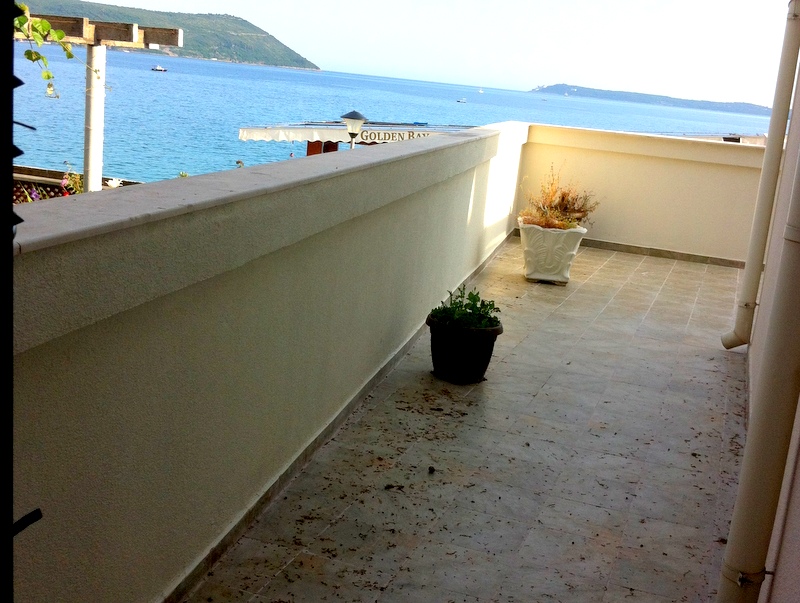 Geräumiger Balkon mit Meerblick in einer Wohnung in Herceg Novi, Montenegro, mit Bodenfliesen und Blumentöpfen.