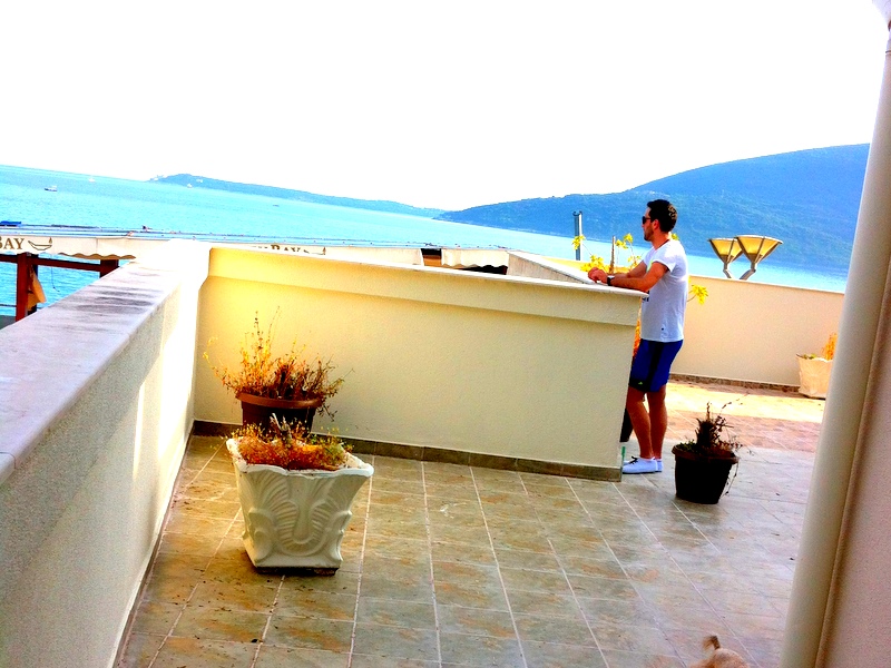 Geräumige Terrasse der Wohnung in Herceg Novi, Montenegro, mit Panoramablick auf das Meer und die Berge, Fliesenboden und Pflanzen.
