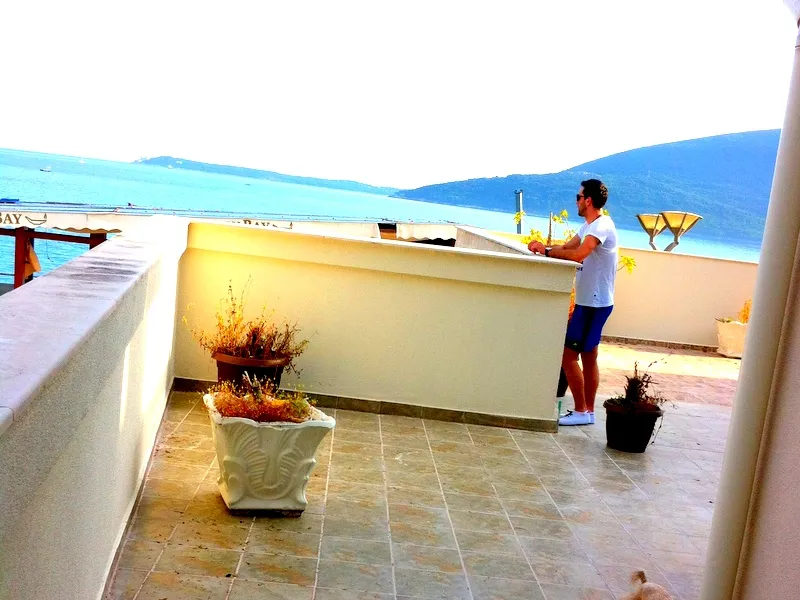 Geräumige Terrasse der Wohnung in Herceg Novi, Montenegro, mit Panoramablick auf das Meer und die Berge, Fliesenboden und Pflanzen.
