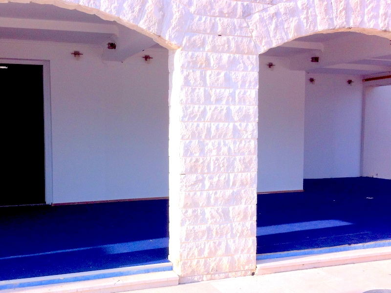 Terrasse der Wohnung in Herceg Novi, Montenegro: Steinbögen, helle Ausstattung und blauer Bodenbelag.