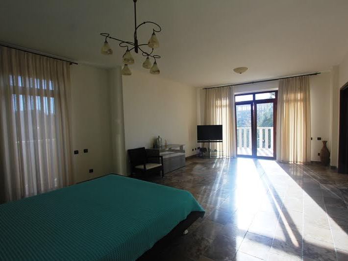 Geräumiges Schlafzimmer in einer Villa in Petrovac, Montenegro: Bett, Marmorboden, Panoramafenster und Zugang zur Terrasse.