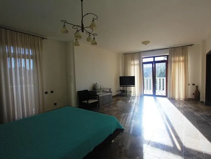 Geräumiges Schlafzimmer in einer Villa in Petrovac, Montenegro: Bett, Marmorboden, Panoramafenster und Zugang zur Terrasse.