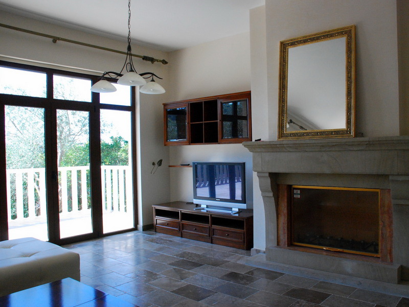 Wohnzimmer mit Kamin und Zugang zur Terrasse in einer Villa, Petrovac, Montenegro: Steinboden, TV-Bereich und Spiegel im Rahmen.