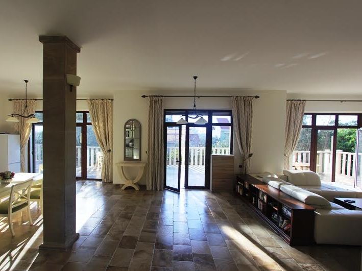 Geräumiges Wohnzimmer mit Steinboden und Zugang zur Terrasse in einer Villa in Petrovac, Montenegro. Moderne Möbel und Dekor.