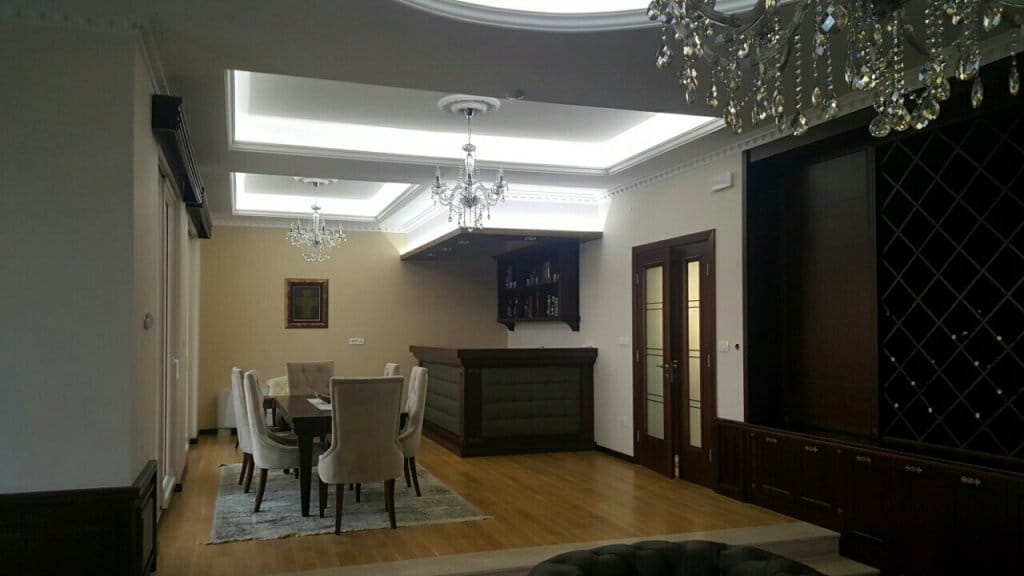 Salon avec bar et coin repas dans une villa à Reževići, Monténégro : intérieur classique avec lustres.