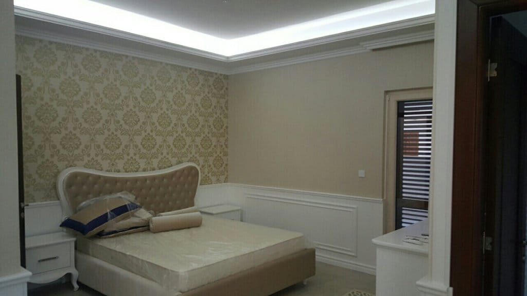 Chambre à coucher de style classique dans une villa à Reževići, Monténégro : lit double, papier peint à motifs et éclairage indirect.