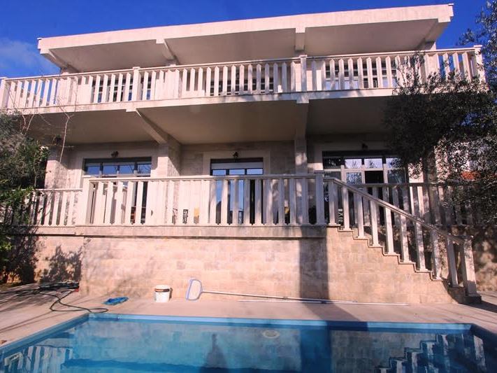 Zweigeschossige Steinvilla mit Pool und Terrassen in Petrovac, Montenegro: Blick auf die Fassade des Gebäudes von der Straße aus.