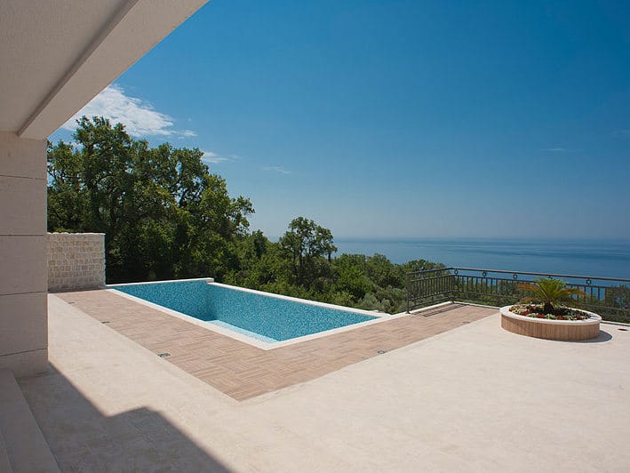 Terrasse avec piscine et vue panoramique sur la mer dans une villa à Reževići, Monténégro : finition moderne et aménagement paysager.