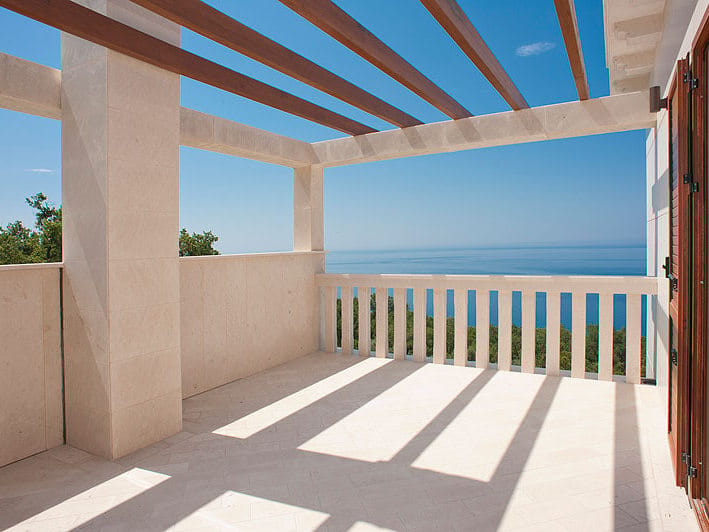 Spacieuse terrasse de villa à Reževići, Monténégro, avec finition en pierre, pergola en bois et vue panoramique sur la mer.