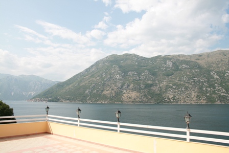 Panoramski pogled sa terase hotela u Stolivu, Crna Gora: otvorena terasa sa belom ogradom i pogledom na Bokokotorski zaliv.