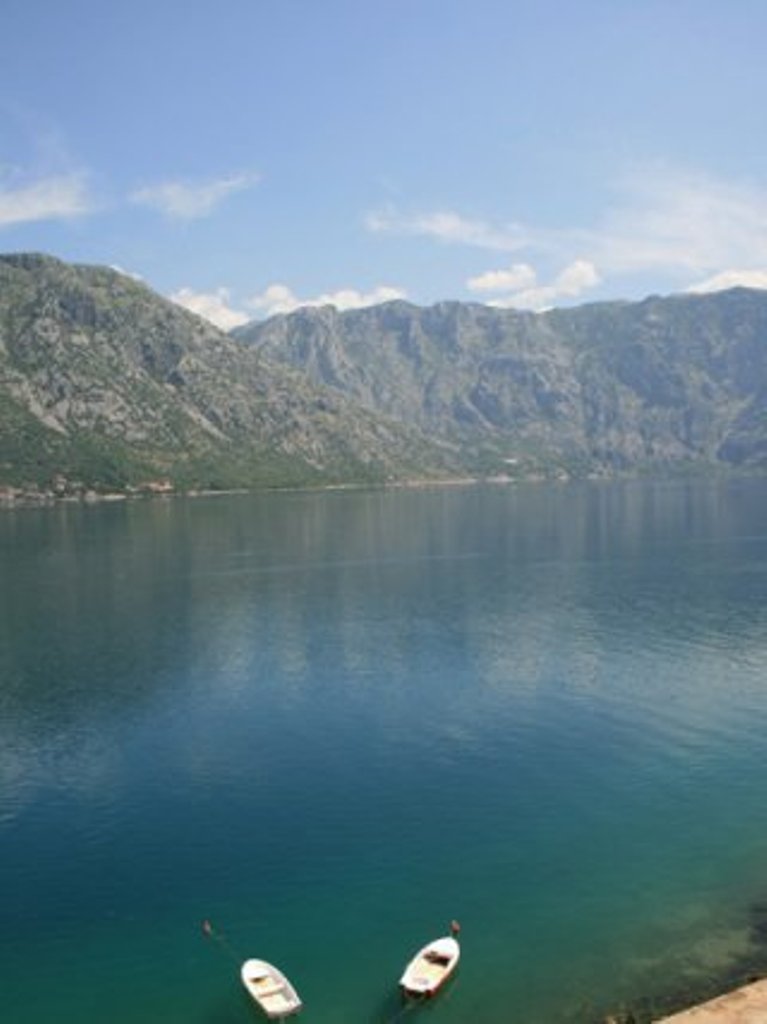 Panoramski pogled na Bokokotorski zaliv i planine iz hotela u Stolivu, Crna Gora, sa čamcima na mirnoj površini vode.