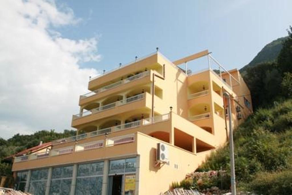 Fasada hotela u Stolivu, Crna Gora: višespratna zgrada sa terasama i panoramskim pogledom na planine i more.