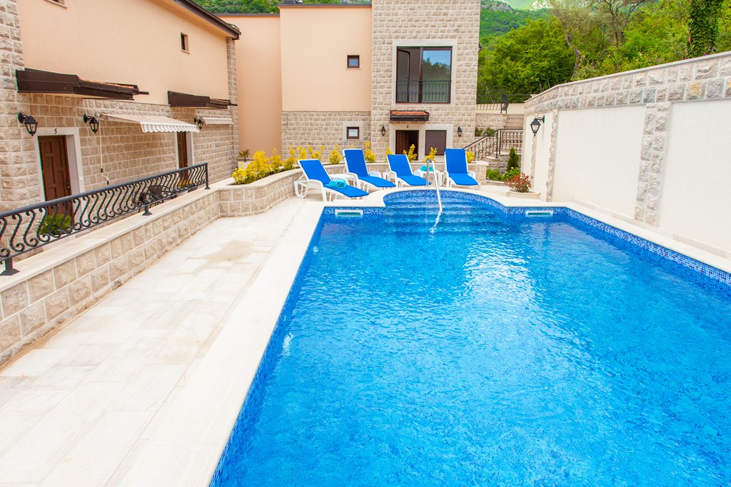 Otvoreni bazen sa ležaljkama pored kamenih apartmana u Kamenovu, Crna Gora.