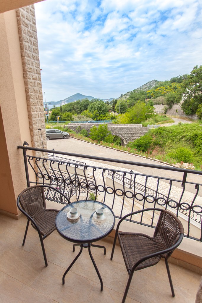 Balkon sa pletenim stolicama i pogledom na planine i more u stanu, Kamenovo, Crna Gora.