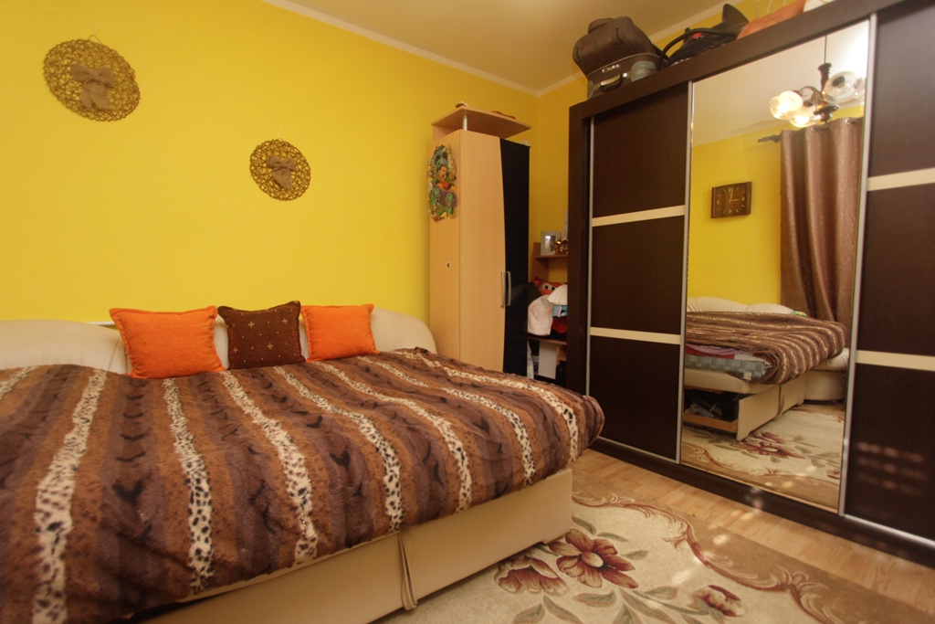 Schlafzimmer mit Doppelbett und Spiegelschiebetürenschrank in einem Haus in Herceg Novi, Montenegro. Gelbe Wände und gemütliches Interieur.