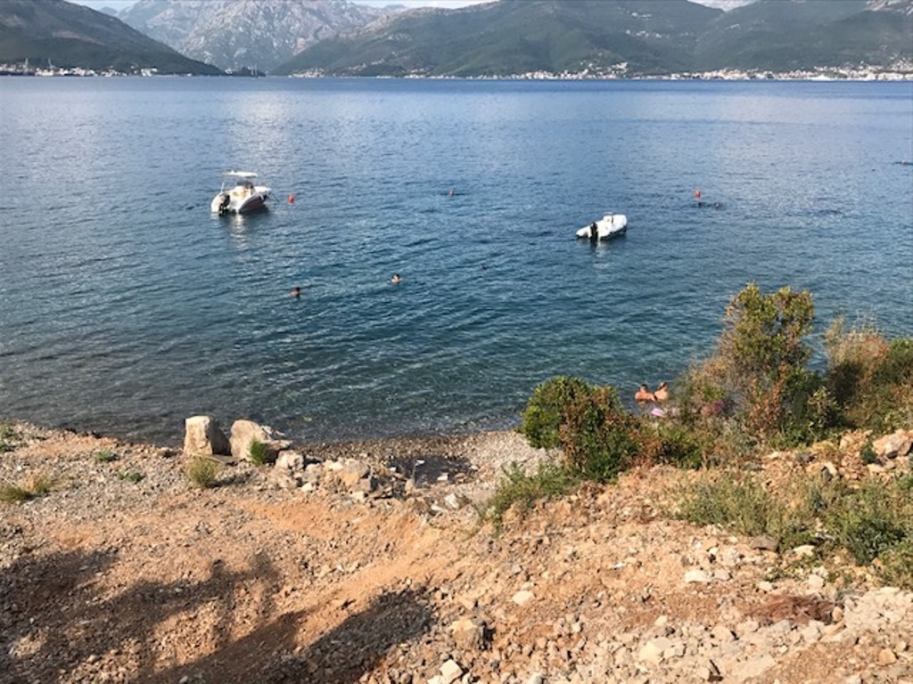 Вид на море и горы с земельного участка в Крашичи, Черногория: частный пляж, катера и панорамный морской пейзаж.