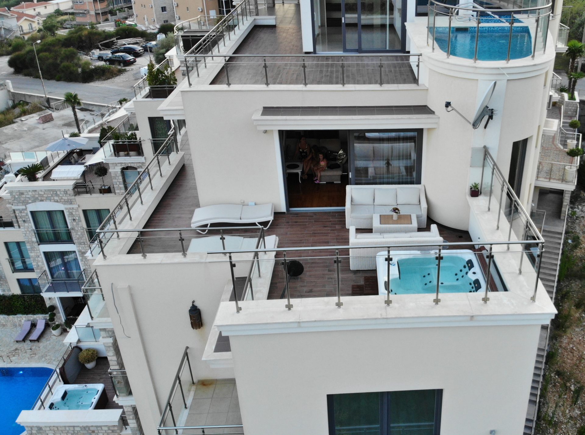 Penthouse-Terrasse in Bečići, Montenegro: Whirlpool, Rattanmöbel, Sonnenliegen und Panoramablick auf das Meer und die Berge.