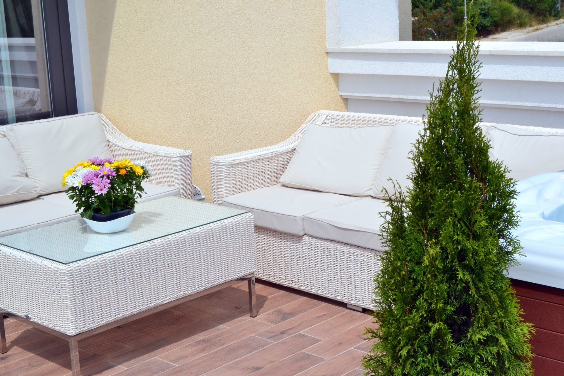 Gemütliche Terrasse mit Rattanmöbeln und Whirlpool in einer Wohnung in Bečići, Montenegro: Blick auf den Balkon mit Blumen und Dekor.