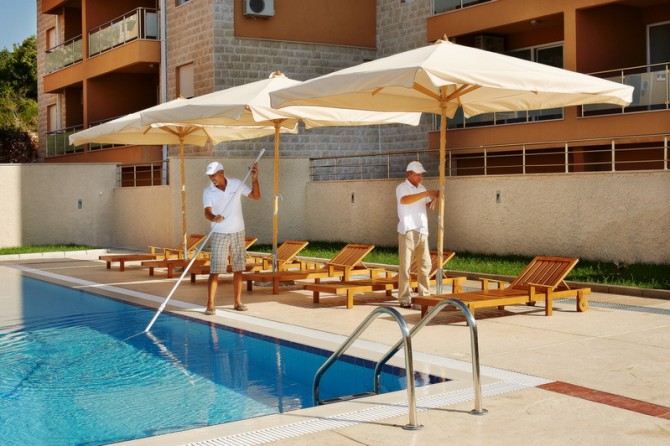 Karadağ, Bečići’deki konut kompleksinde havuz alanı: şezlonglar, şemsiyeler ve modern çevre düzenlemesi.