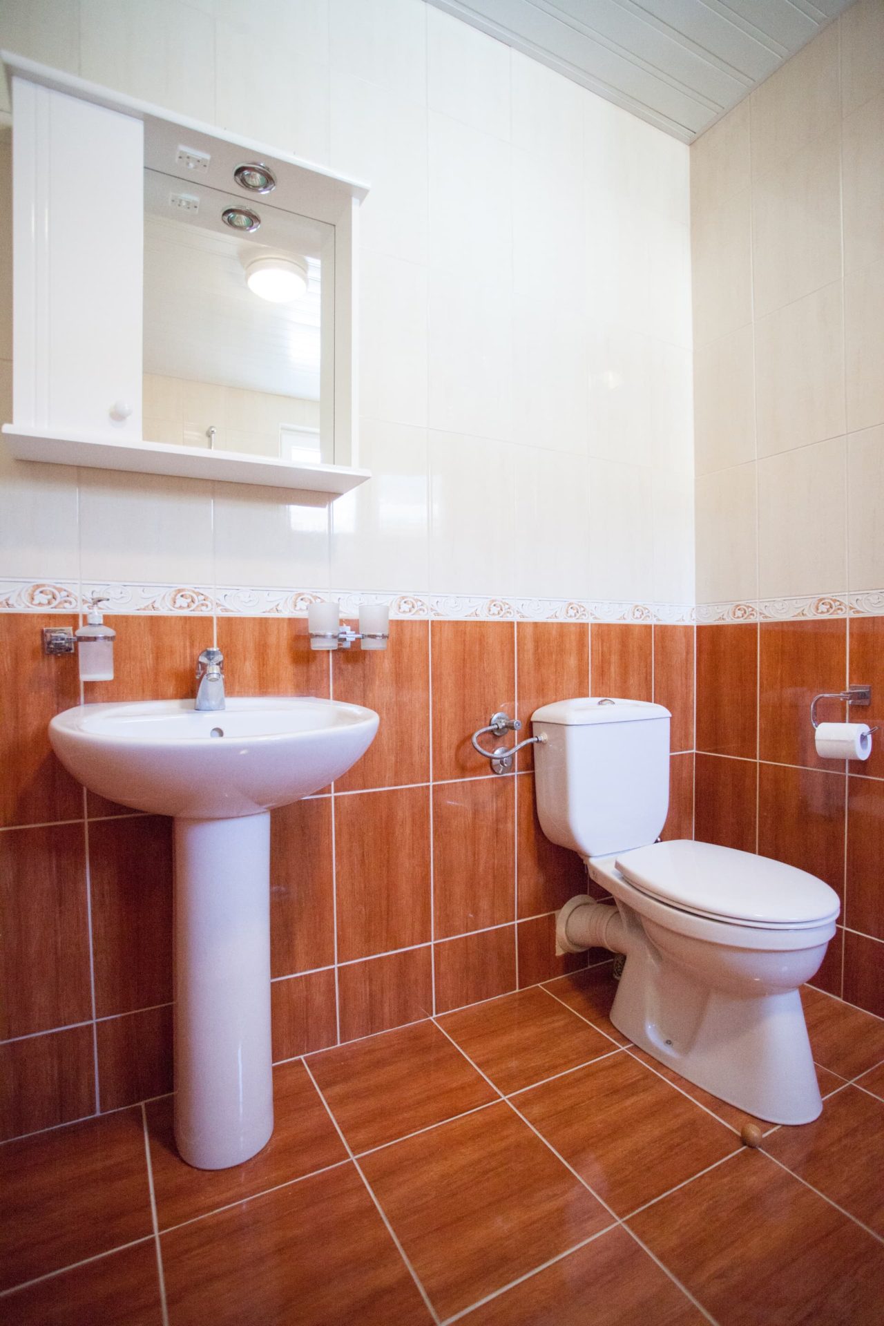 Bečići, Karadağ’daki penthouse’ta aydınlık banyo: beyaz sıhhi tesisat, duvarlarda terrakota fayans kaplama.