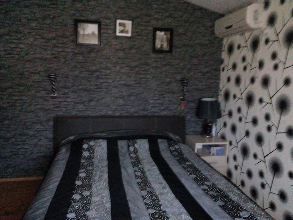 Bedroom in an apartment in Baošići, Montenegro: double bed, patterned wallpaper, bedside table, and air conditioner.