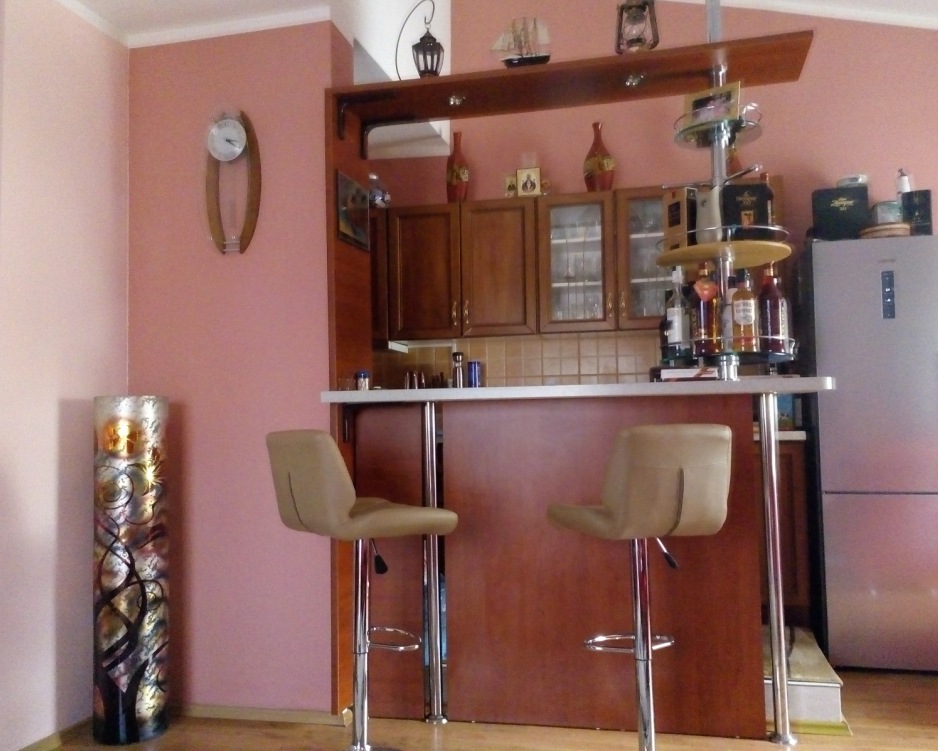 Kitchen with a bar counter and wooden cabinets in an apartment, Baošići, Montenegro. Modern interior with decor.