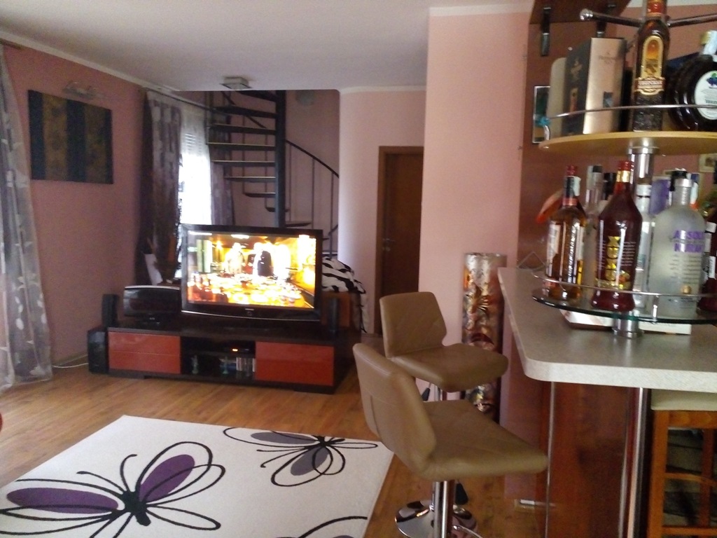 Living room with a bar counter and spiral staircase in an apartment in Baošići, Montenegro: modern interior with TV area.