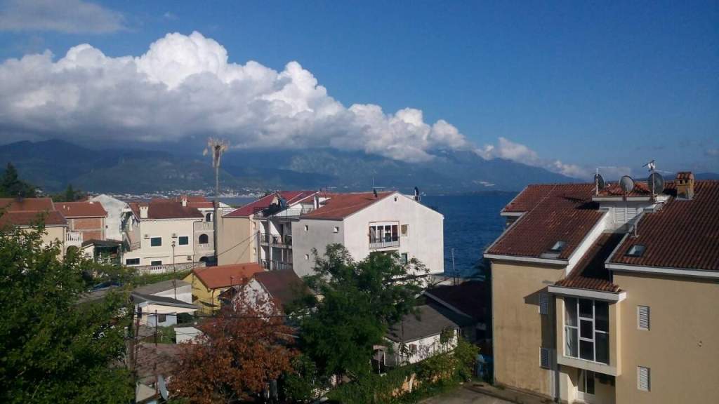 Sea and mountain view from an apartment in Baošići, Montenegro: a panoramic view of a residential area with houses and terraces.