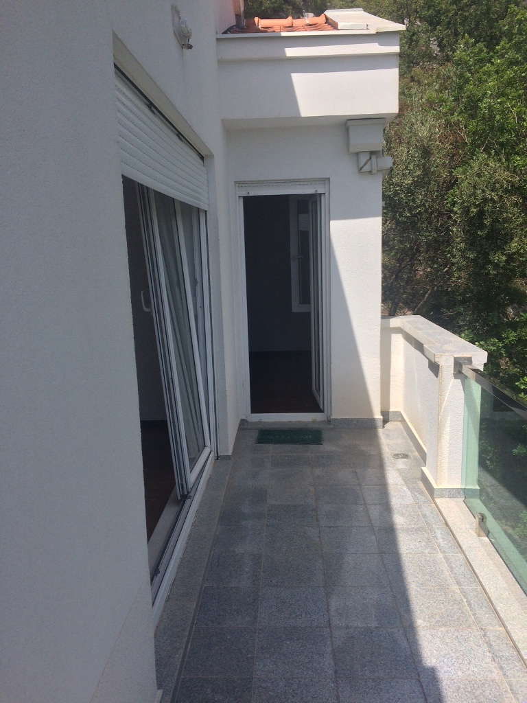 Prostran balkon sa kamenim podom i staklenom ogradom u stanu u Petrovcu, Crna Gora.